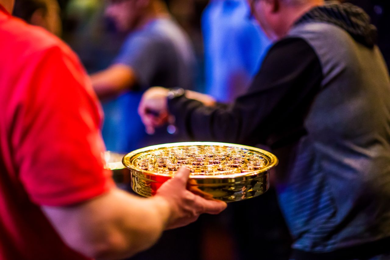 About A close-up of a communion tray being passed in a church gathering, showcasing a spiritual moment.